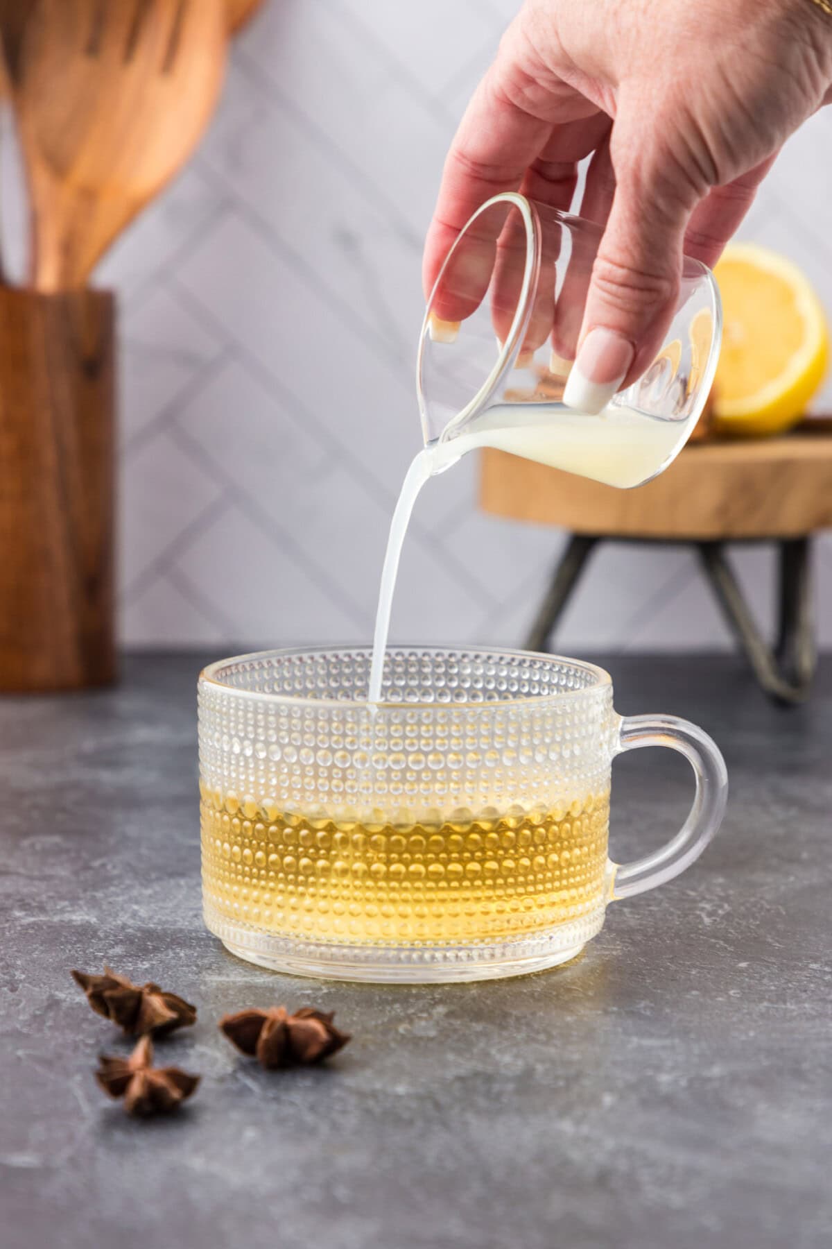 pouring lemon juice into glass with whiskey and water