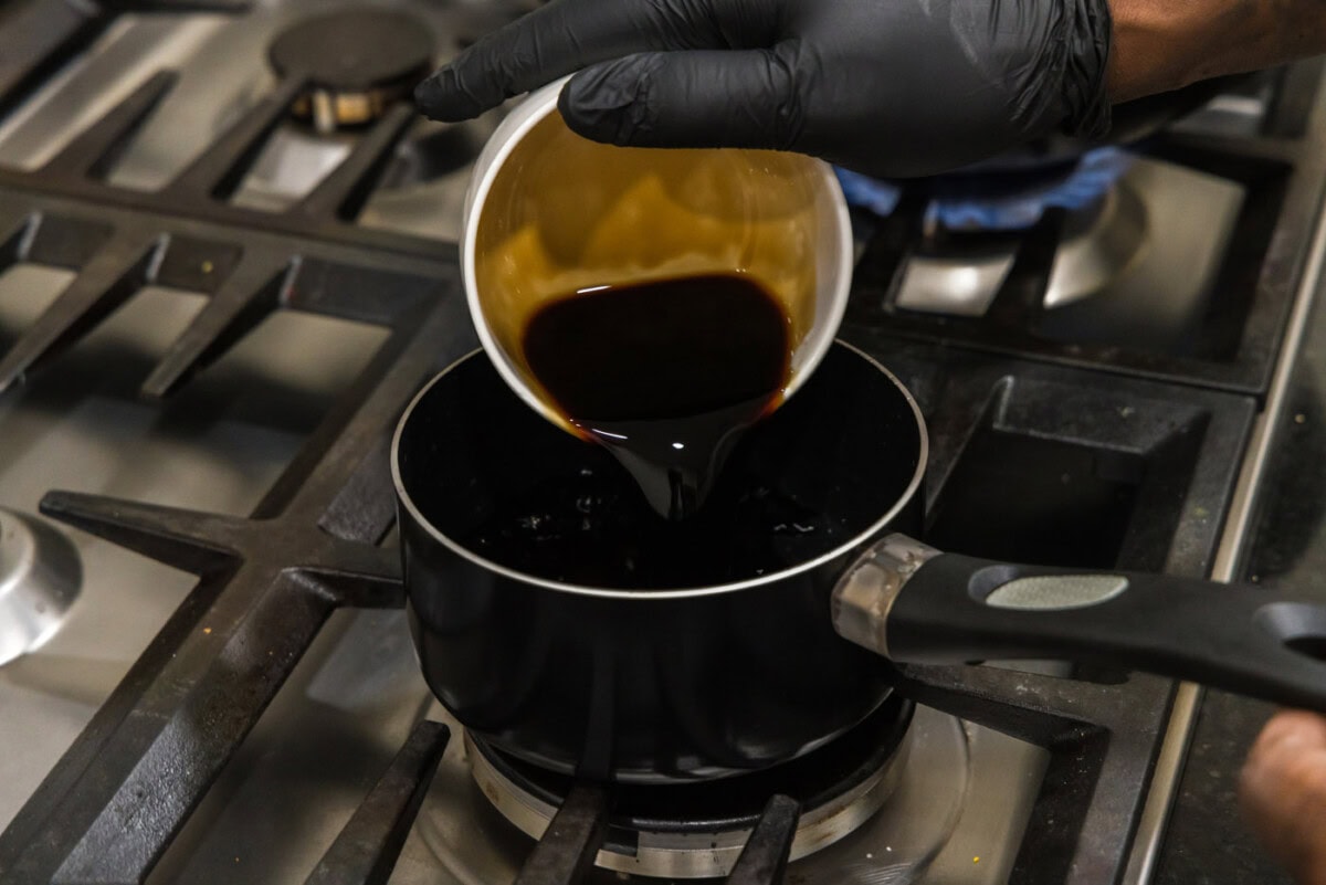 pouring soy sauce into a saucepan