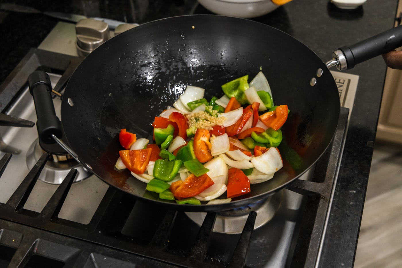 stir frying onion and bell peppers in a wok
