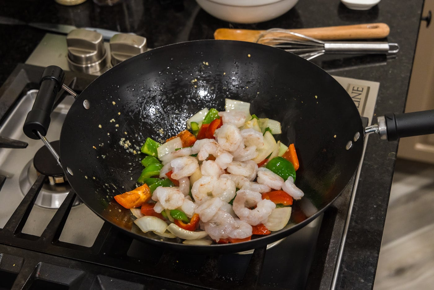 adding shrimp to wok with vegetables