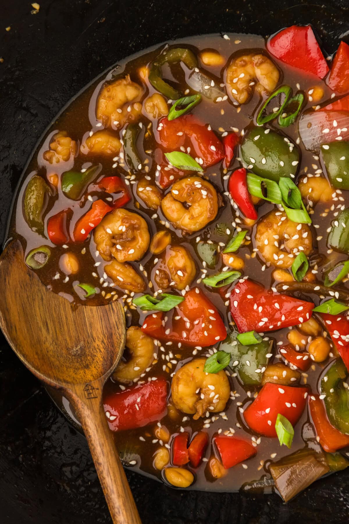 Close up photo of a wok of Kung Pao Shrimp with a spoon in it
