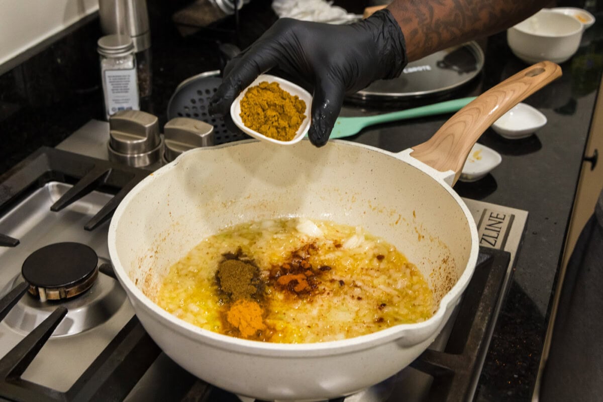 adding spices to curry in a saucepan