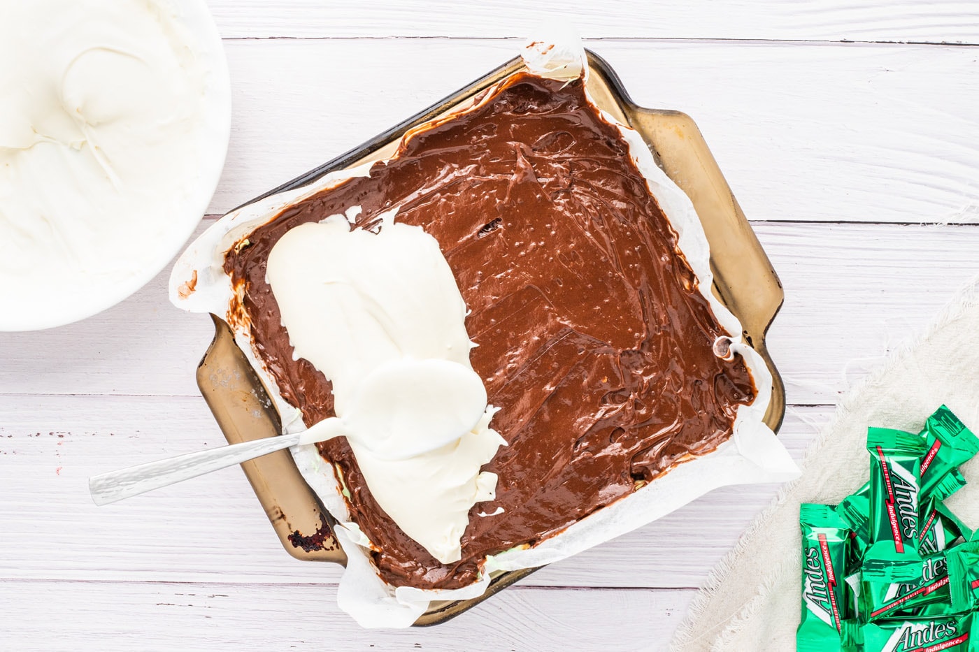 spreading thickened whipped cream over chocolate pudding layer in mint chocolate dream bars