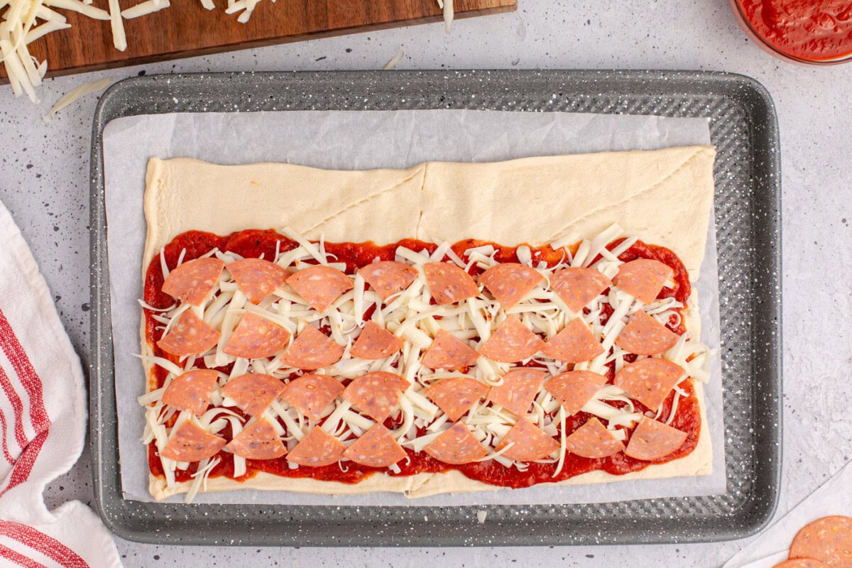 sliced pepperoni on top of pizza crescent roll dough