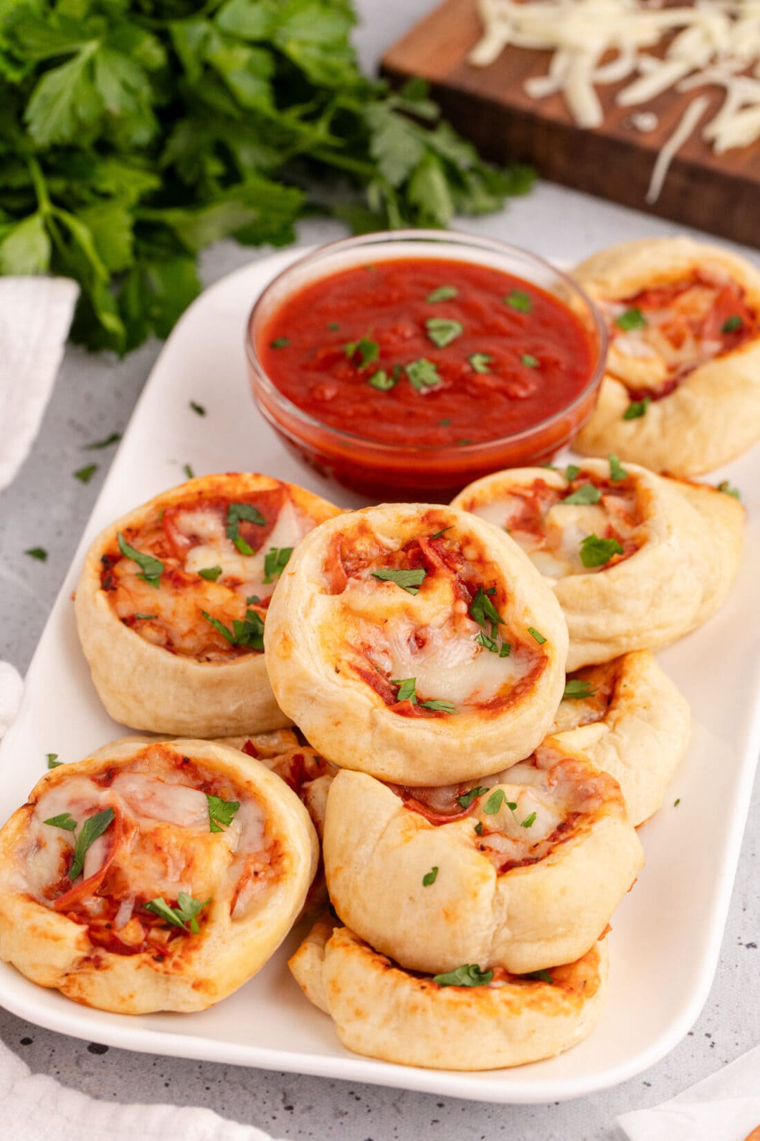 Pizza Pinwheels on a platter with pizza sauce in a bowl