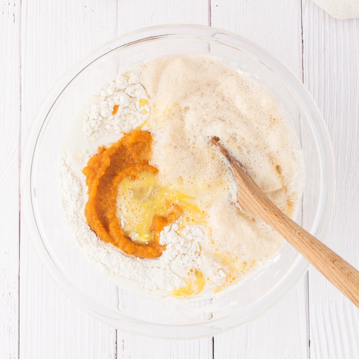 mixing butter, eggs, vanilla, pumpkin puree, warm milk, and yeast mixture