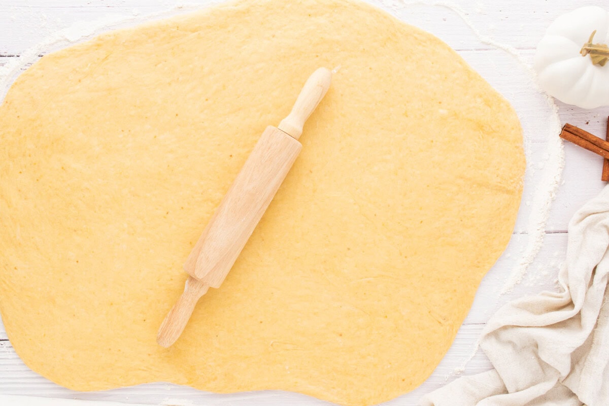 rolling out cinnamon roll dough with a rolling pin