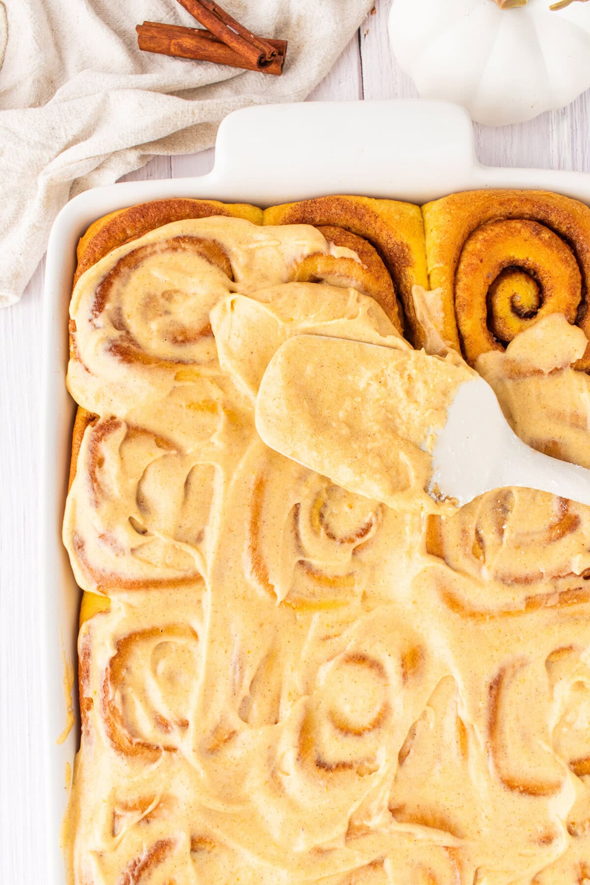 Frosting being spread onto Pumpkin Cinnamon Rolls
