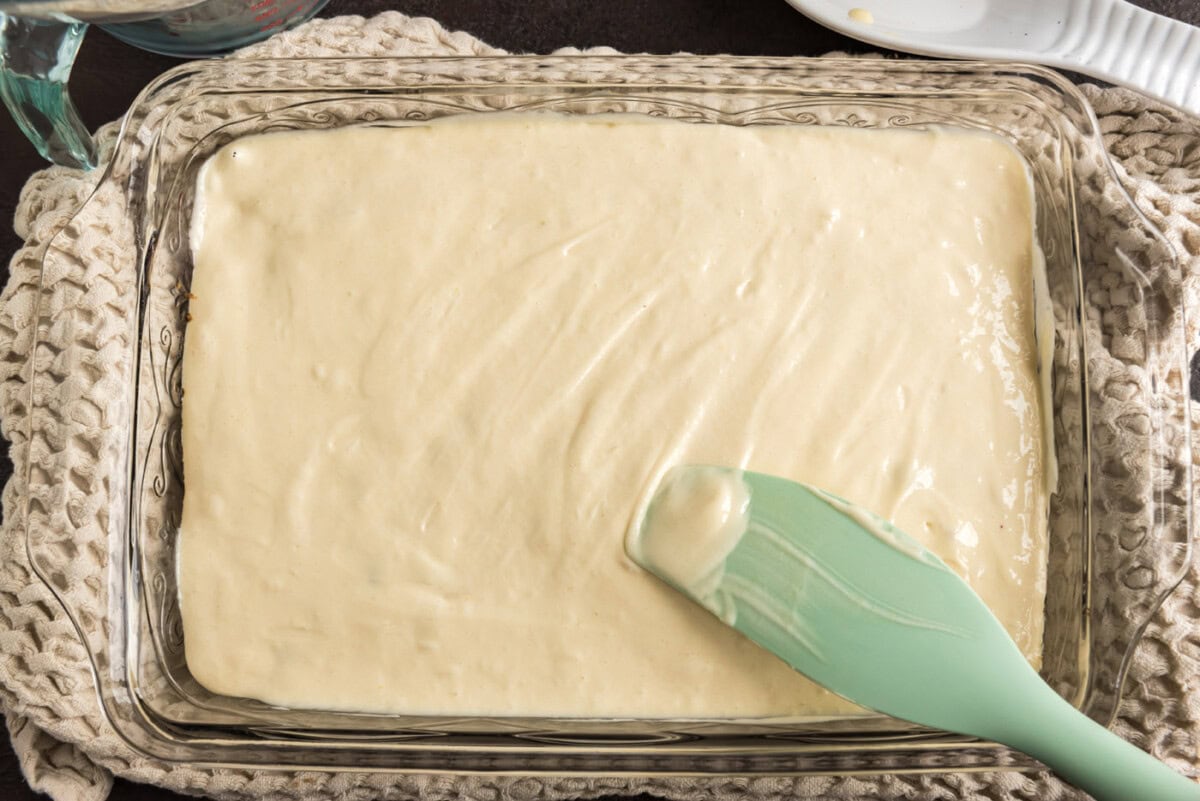 spreading cake batter over raspberries and brown sugar mixture