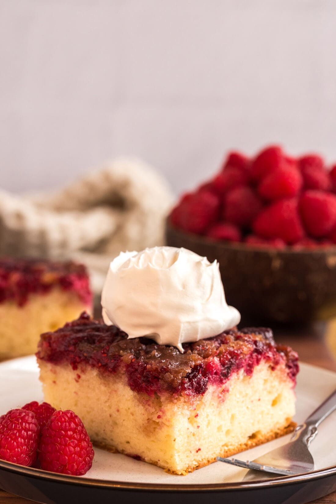 Raspberry Upside Down Cake on a plate topped with whipped cream