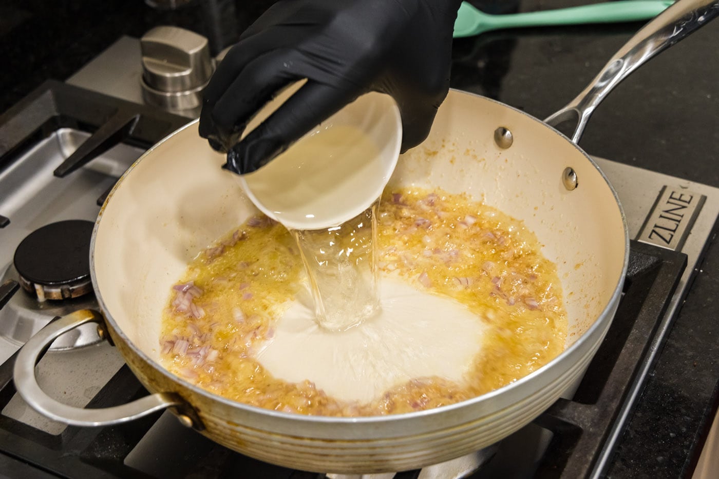 pouring white wine into skillet with butter and shallots