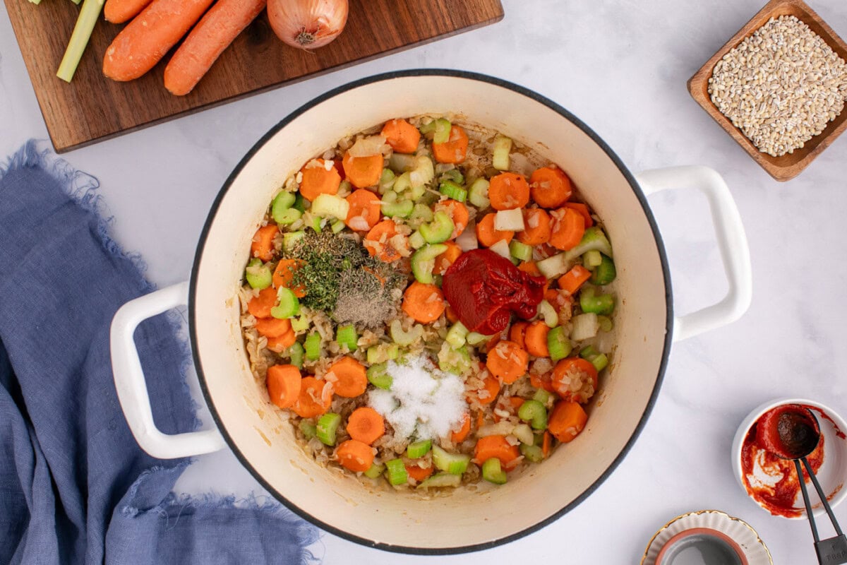 herbs, spices, and tomato paste added to soup pot with vegetables