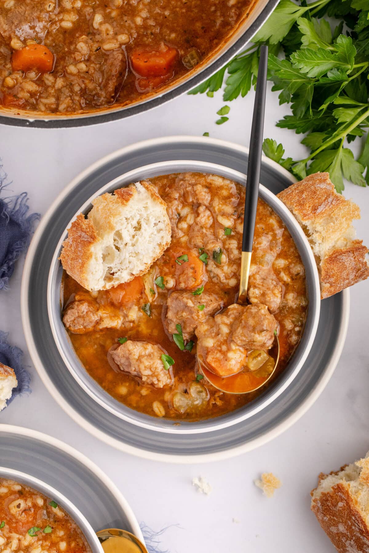 Bowl of Beef Barley Soup with a spoon in it and bread on top