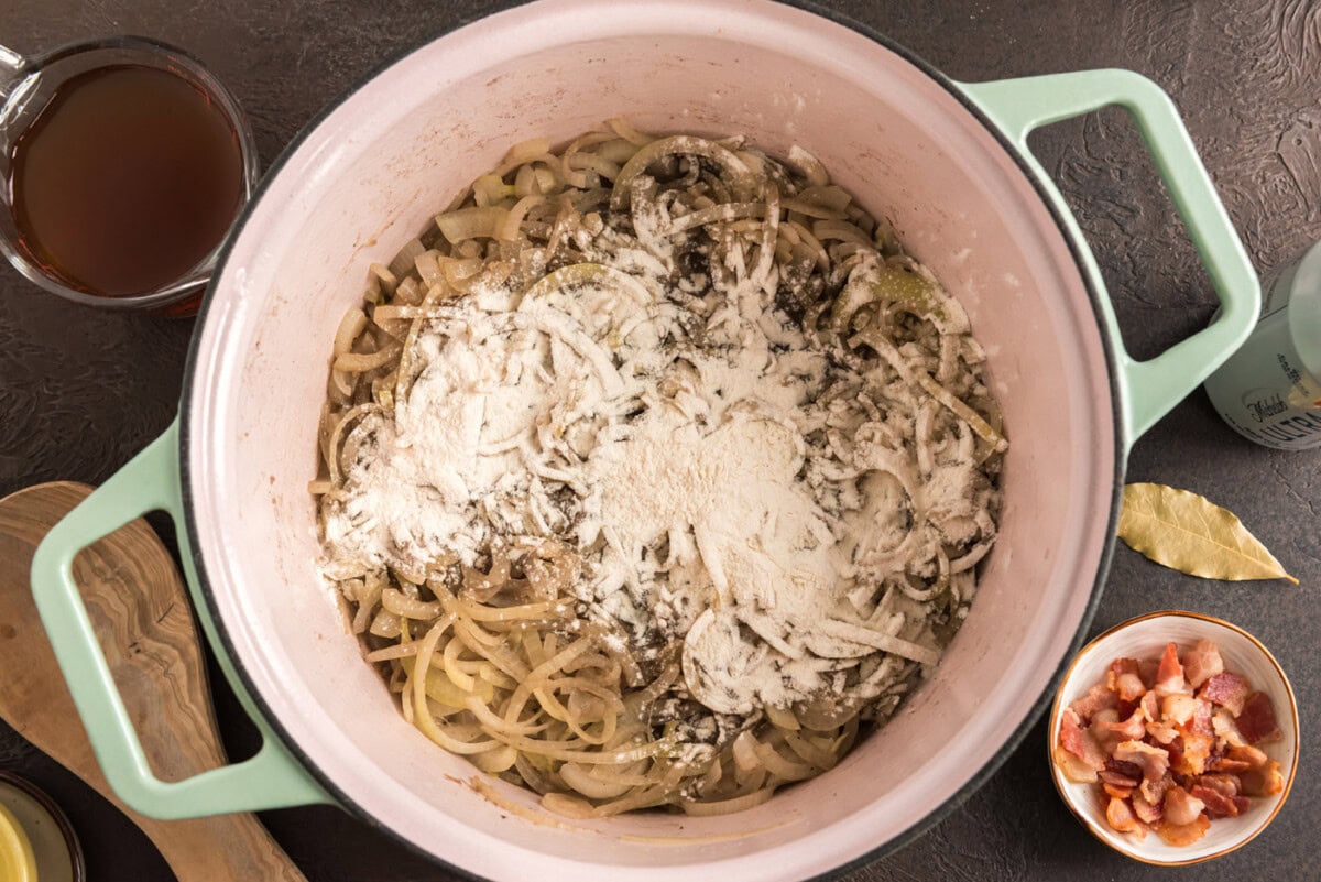 adding flour to dutch oven with onions