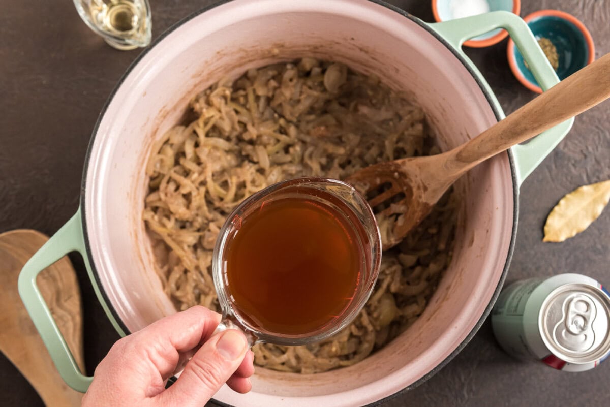 pouring broth into dutch oven with onion mixture
