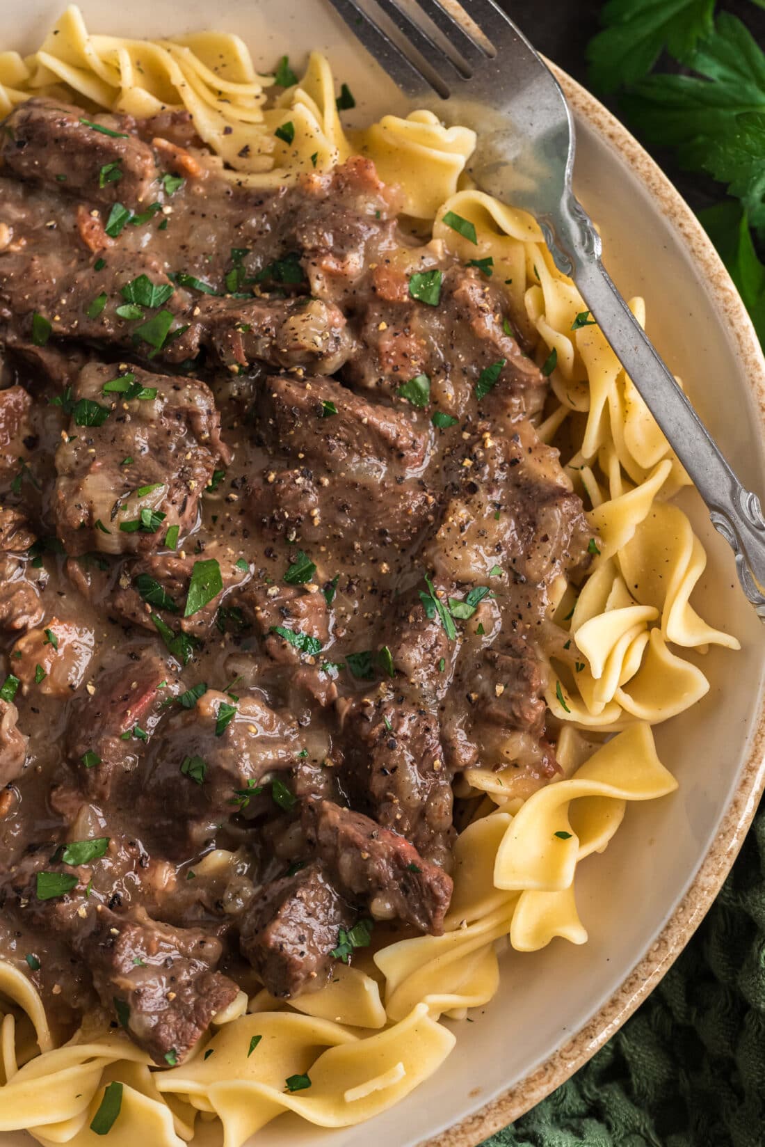 Overhead photo of a half a plate of Beef Carbonnade served over noodles
