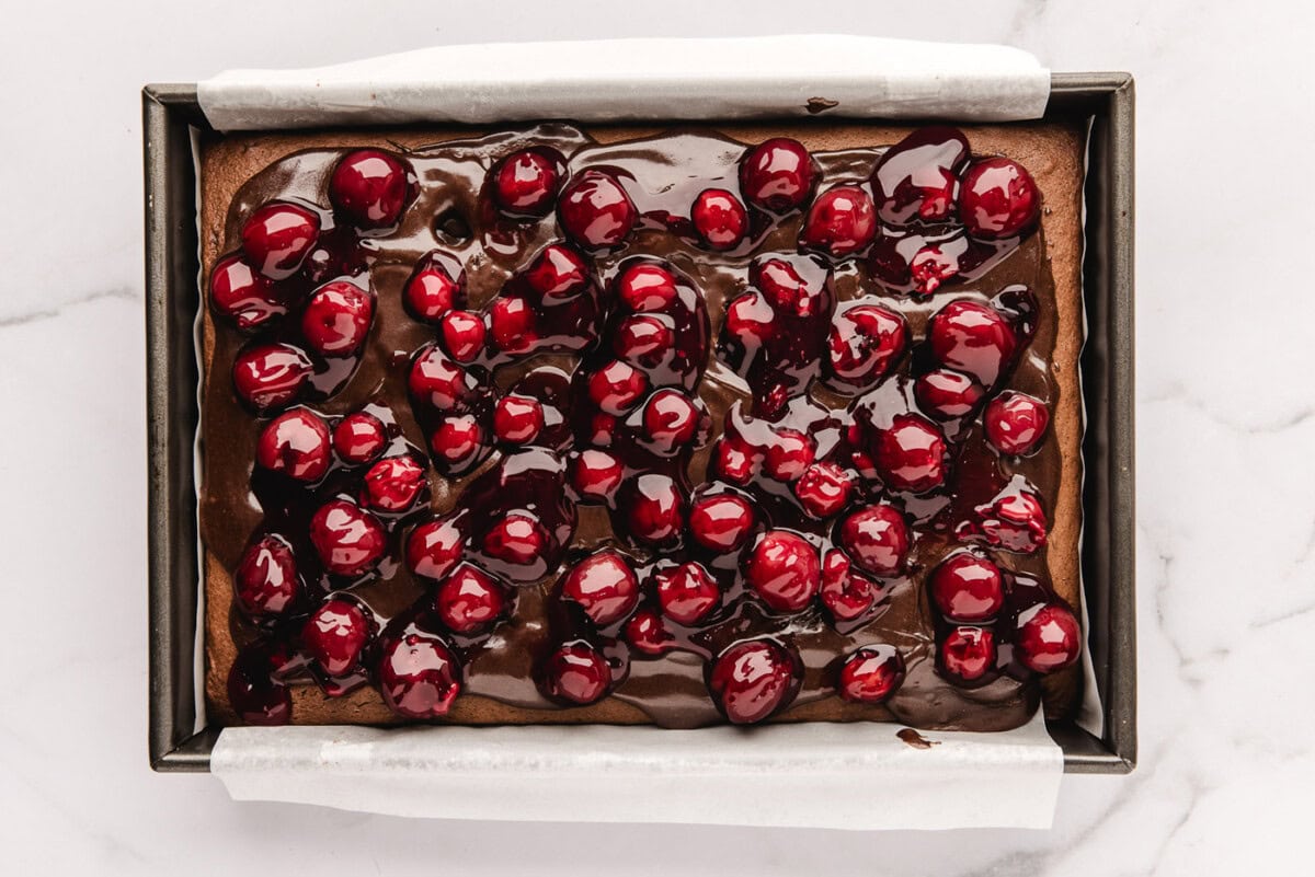 cherry pie filling added on top of fudge sauce and chocolate cake