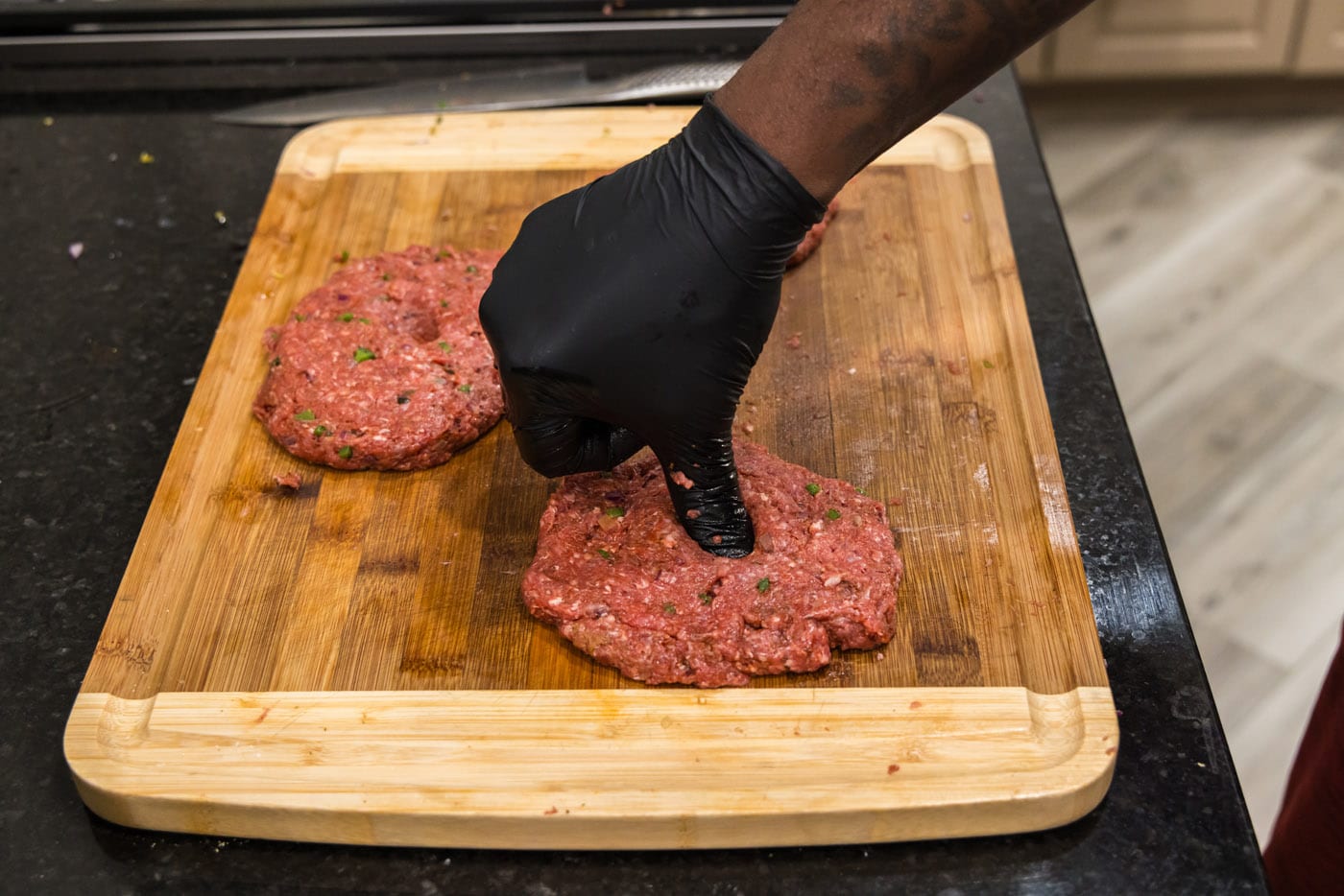 pressing thumb into center of bison burgers