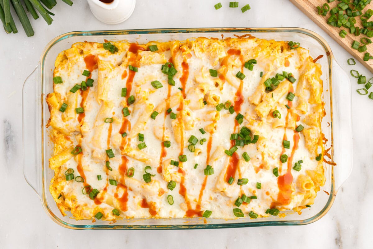 overhead of buffalo chicken casserole with hot sauce and sliced green onion garnish