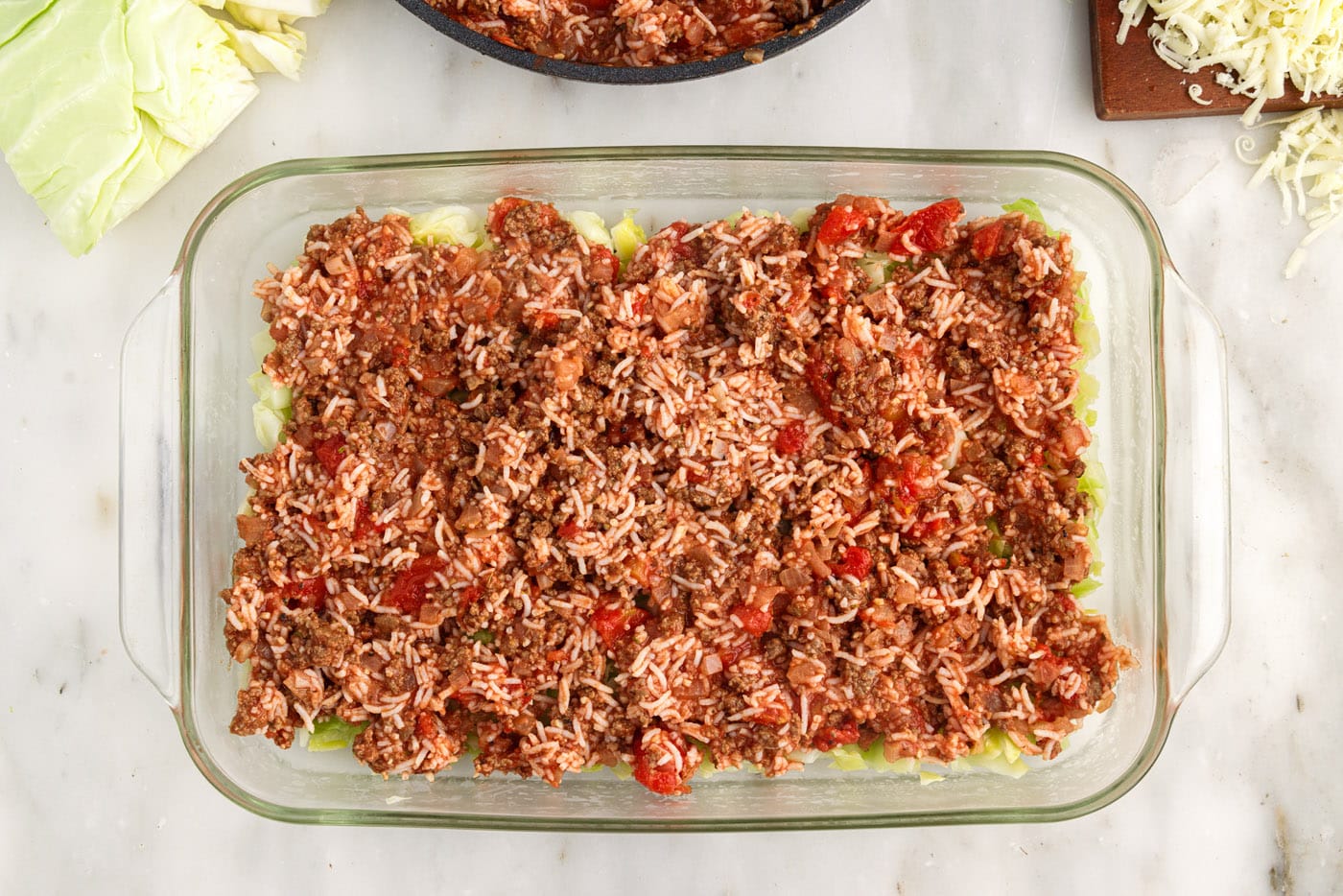 ground beef and rice mixture on top of cabbage in a dish