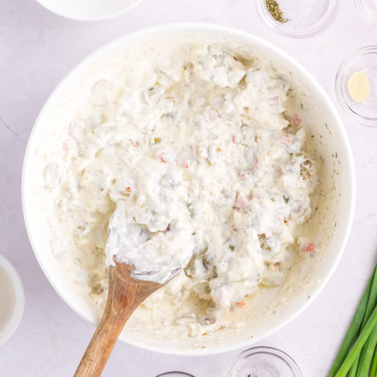mixing dirty martini dip with a wooden spoon