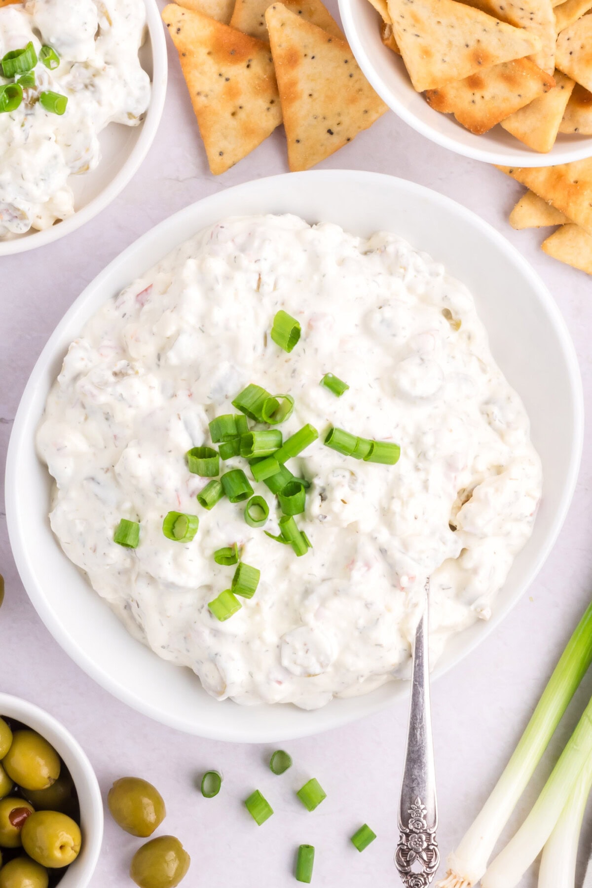 Bowl of Dirty Martini Dip with crackers and olives on the side