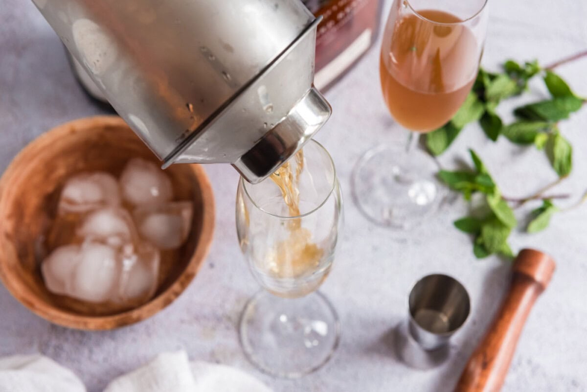 pouring mint julep into champagne glass