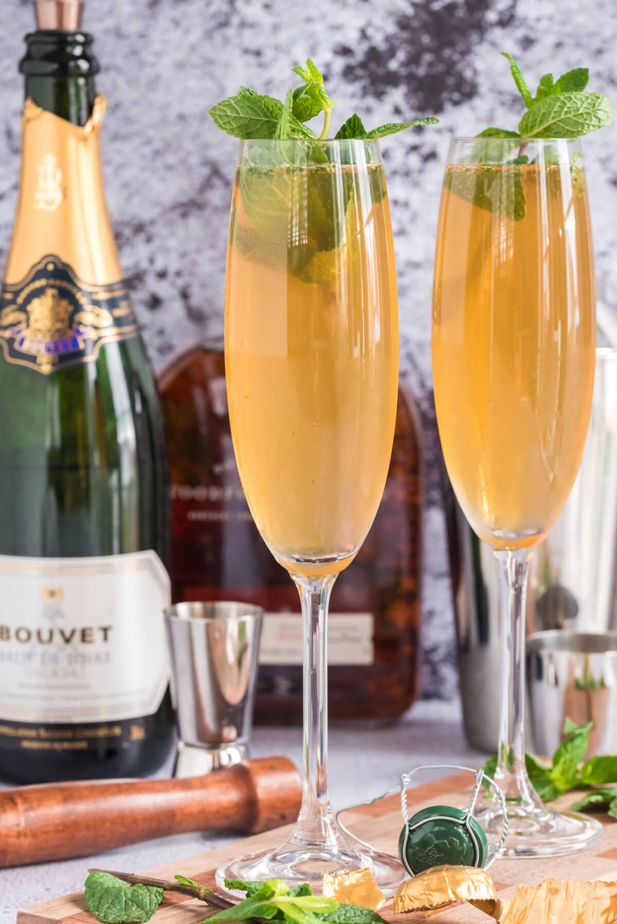 Two Fizzy Julep cocktails with extra champagne in the background
