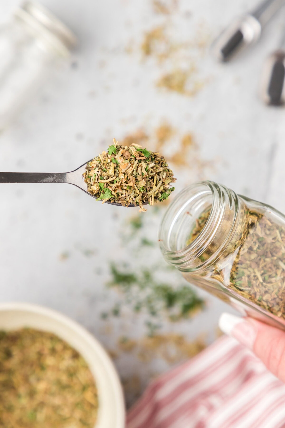 Spoonful of Italian Seasoning pulled out of a seasoning jar