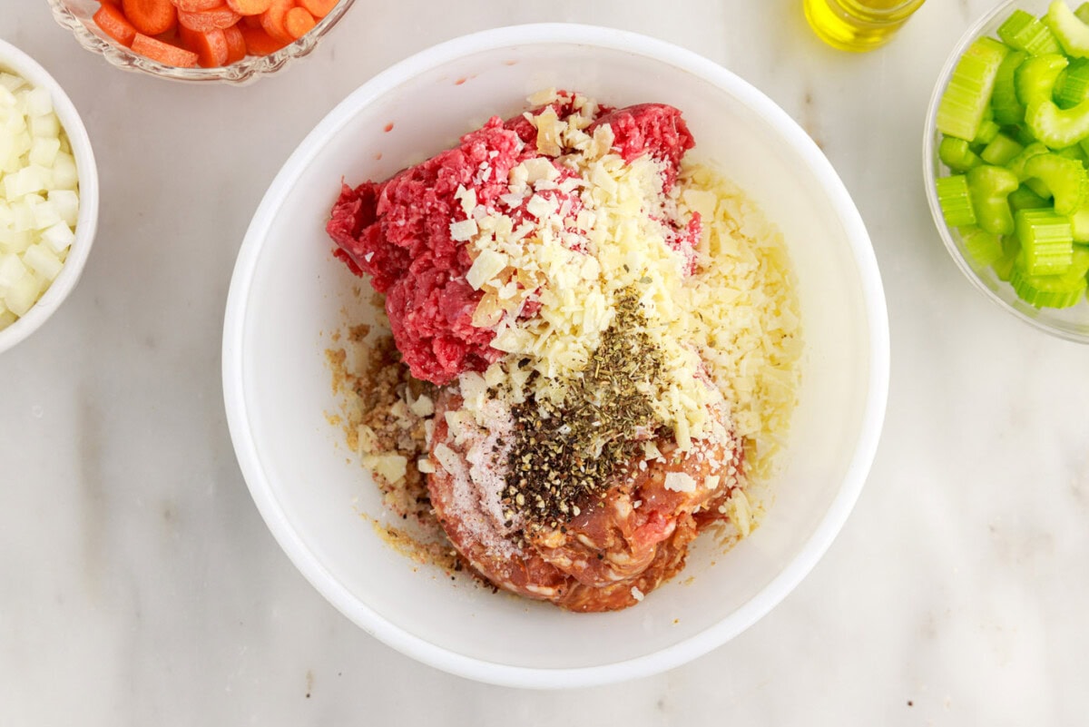 ground beef, seasoning, sausage, and bread crumb mixture in bowl
