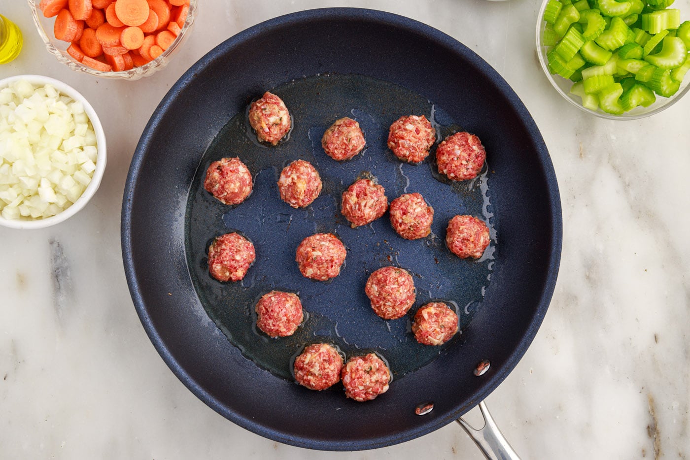 Italian meatballs searing in a skillet