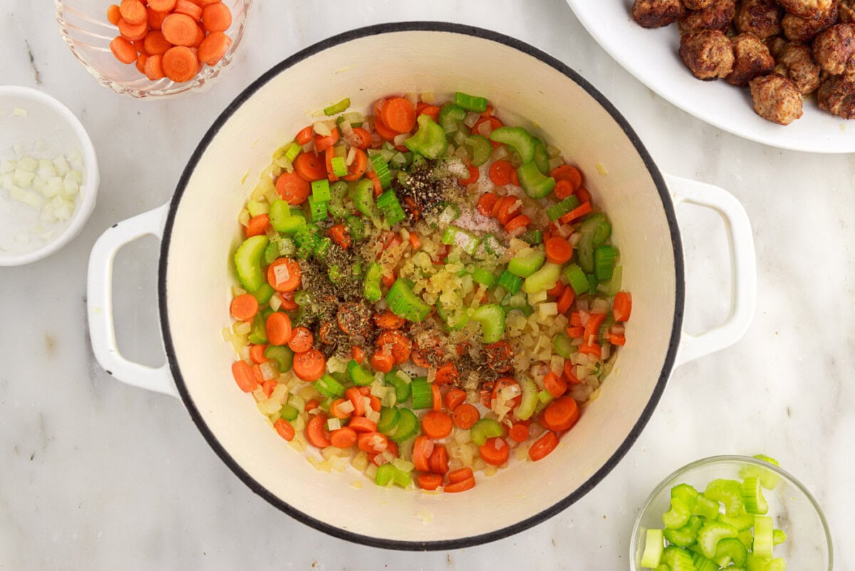 seasoning sprinkled over carrots, celery, and onion in a soup pot