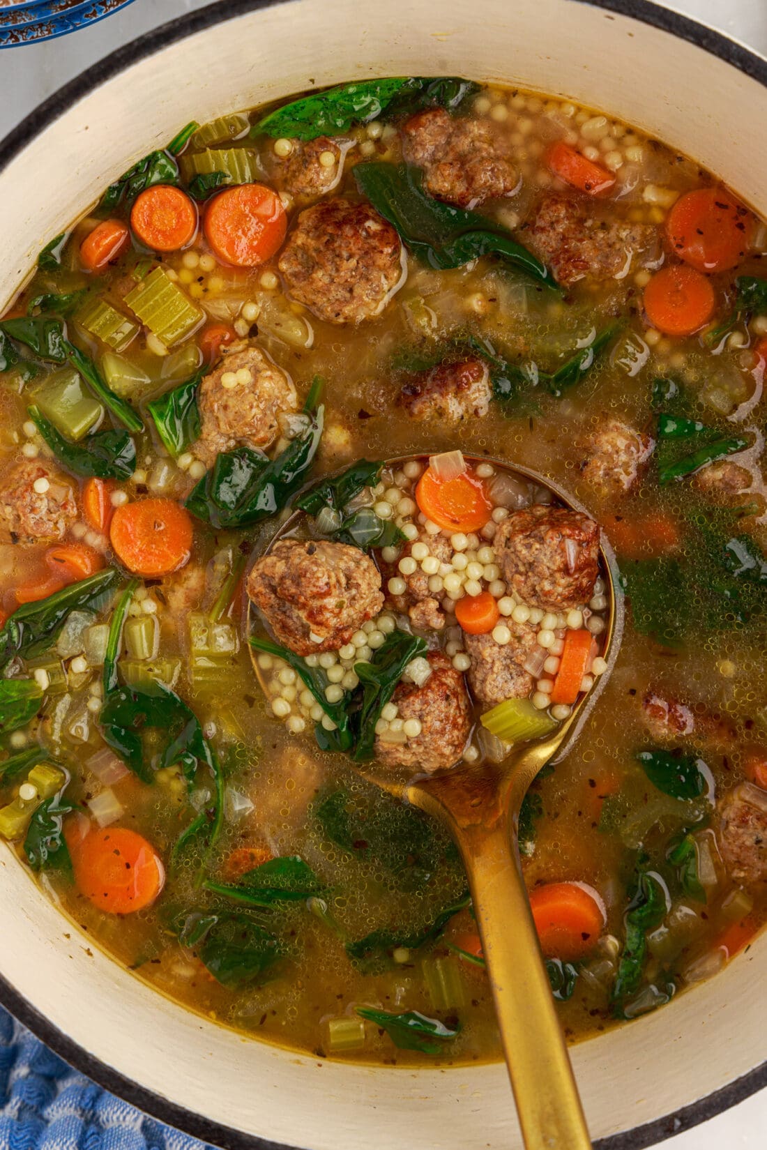 Ladle of Italian Wedding Soup held in a pot of soup