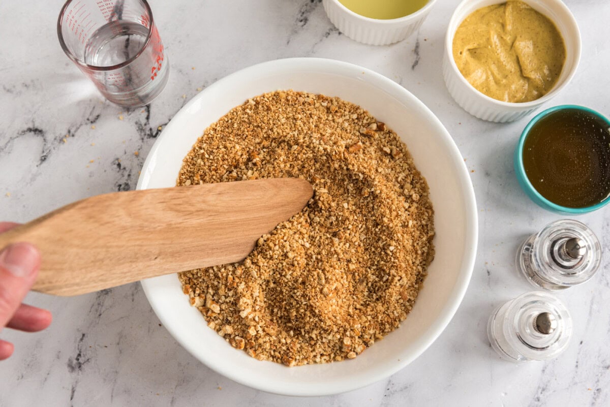 mixing crushed pretzel and walnuts in a bowl