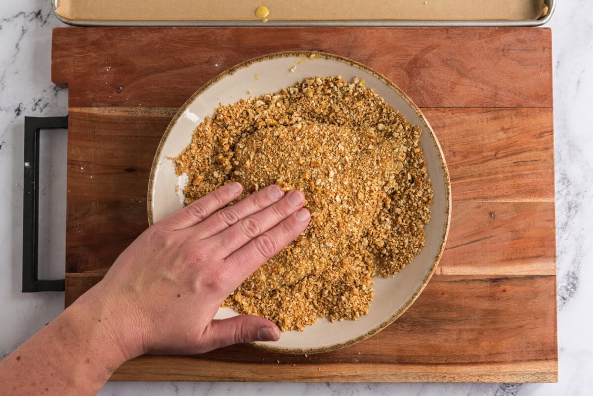 coating honey mustard chicken in crushed pretzel mixture