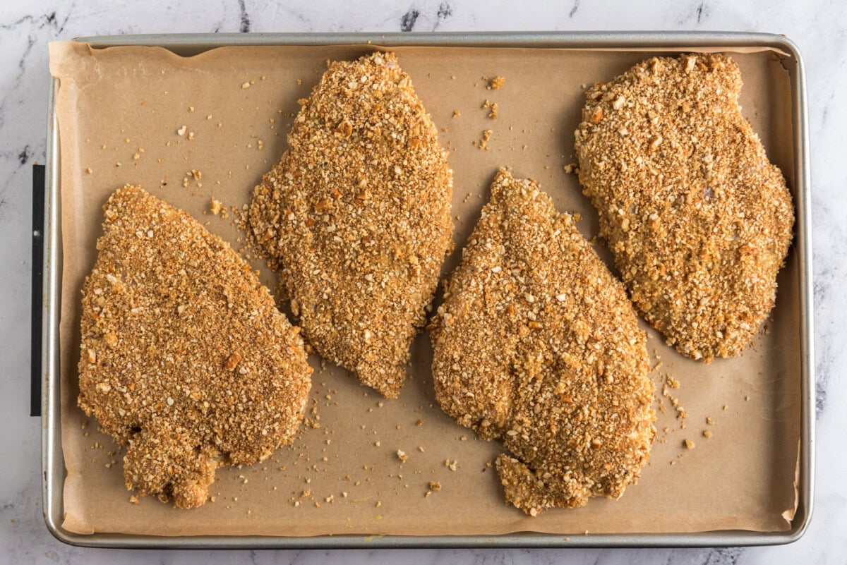 pretzel coated chicken breasts on a baking sheet