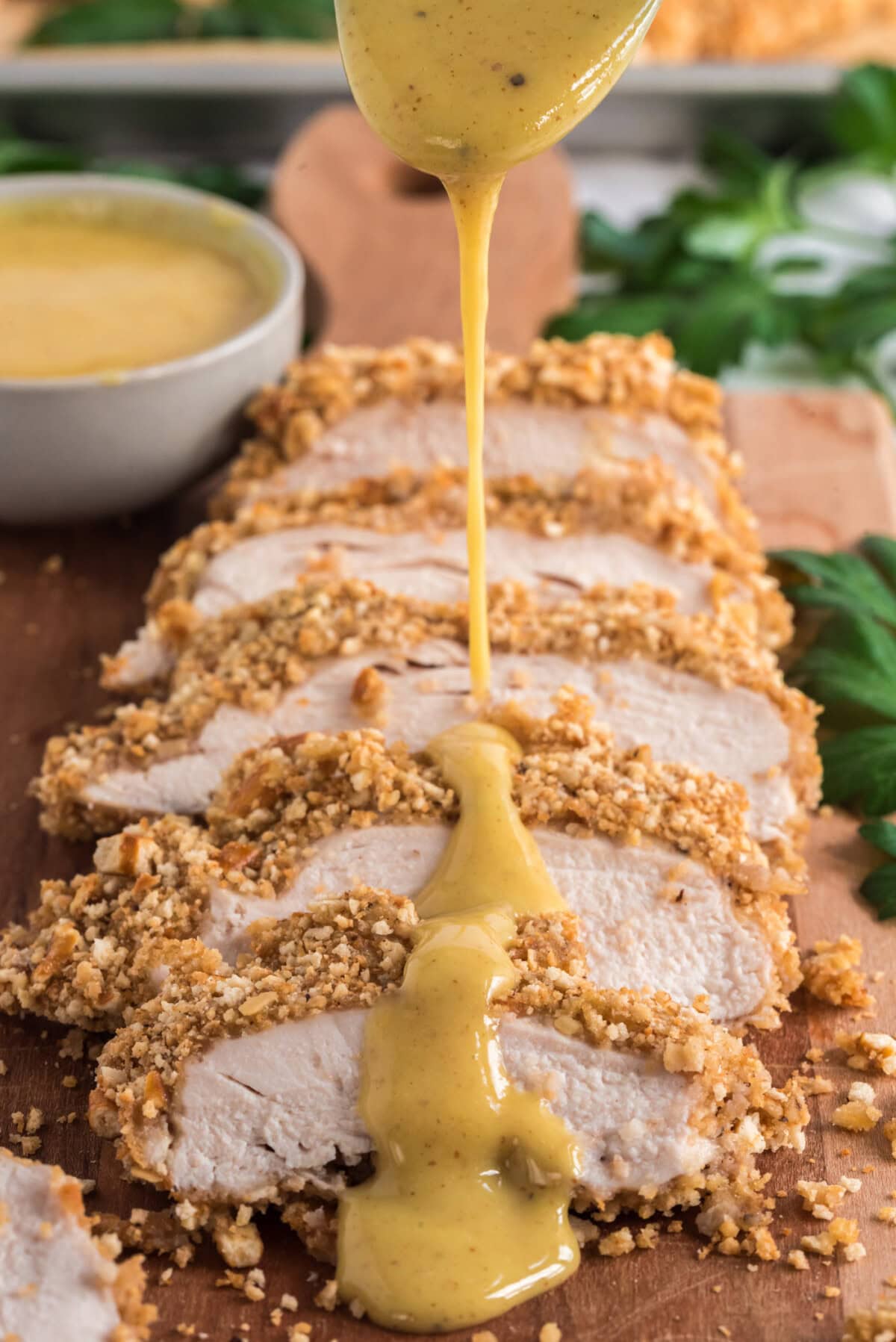 Honey mustard dressing being drizzled over Pretzel Chicken