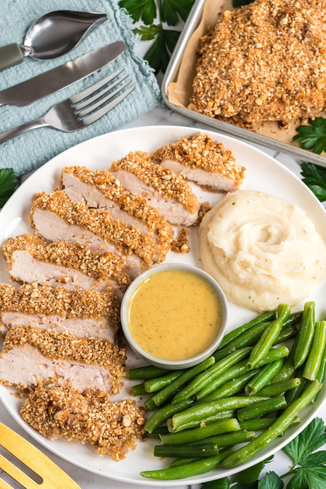 Sliced Pretzel Chicken plated with mashed potatoes and green beans