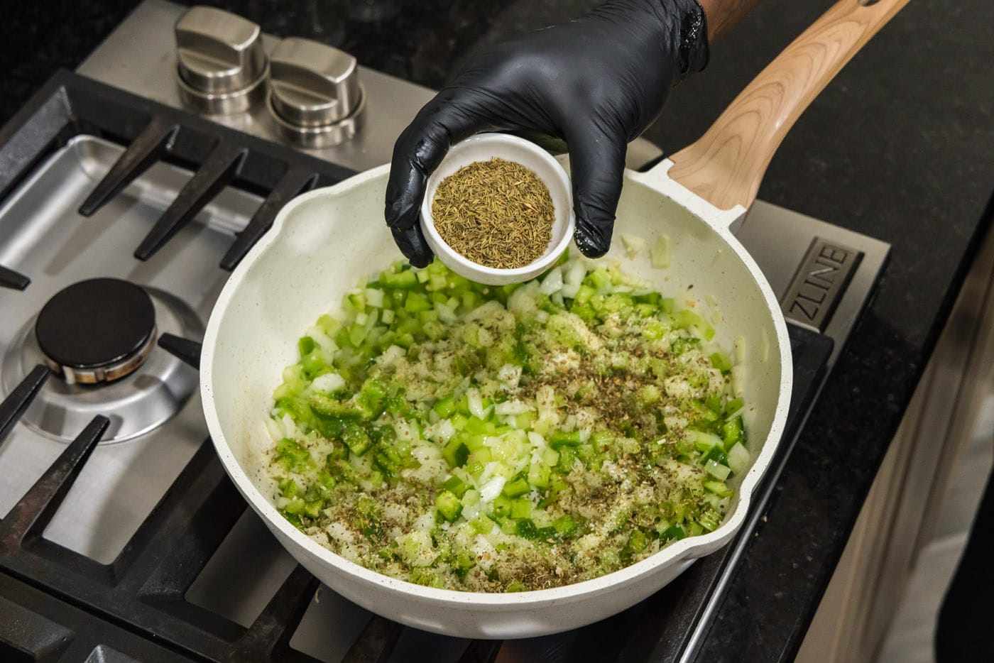 adding spices to skillet of green pepper, onion, and celery