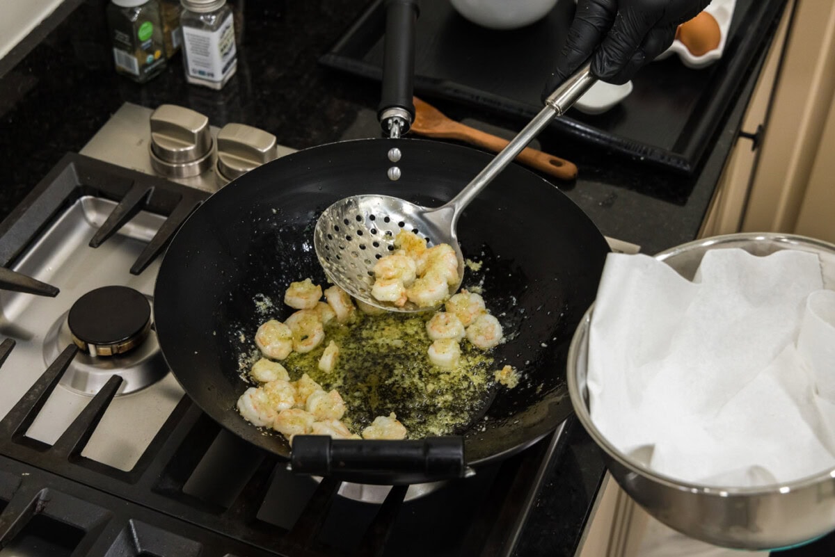 removing cooked shrimp from oil in a wok