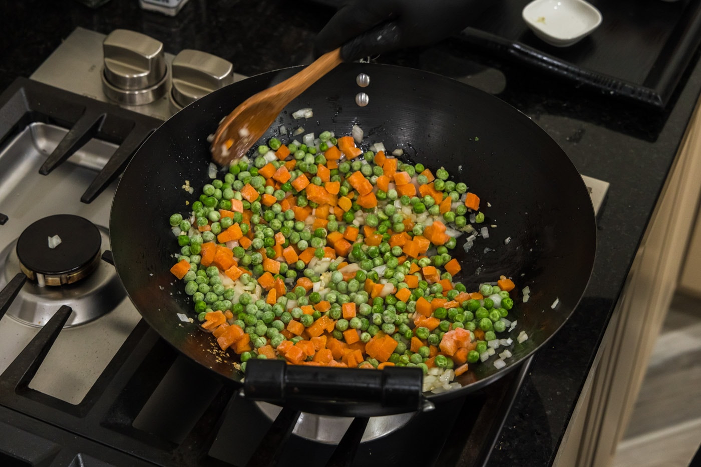 stirring peas and carrots into cooked onion and garlic