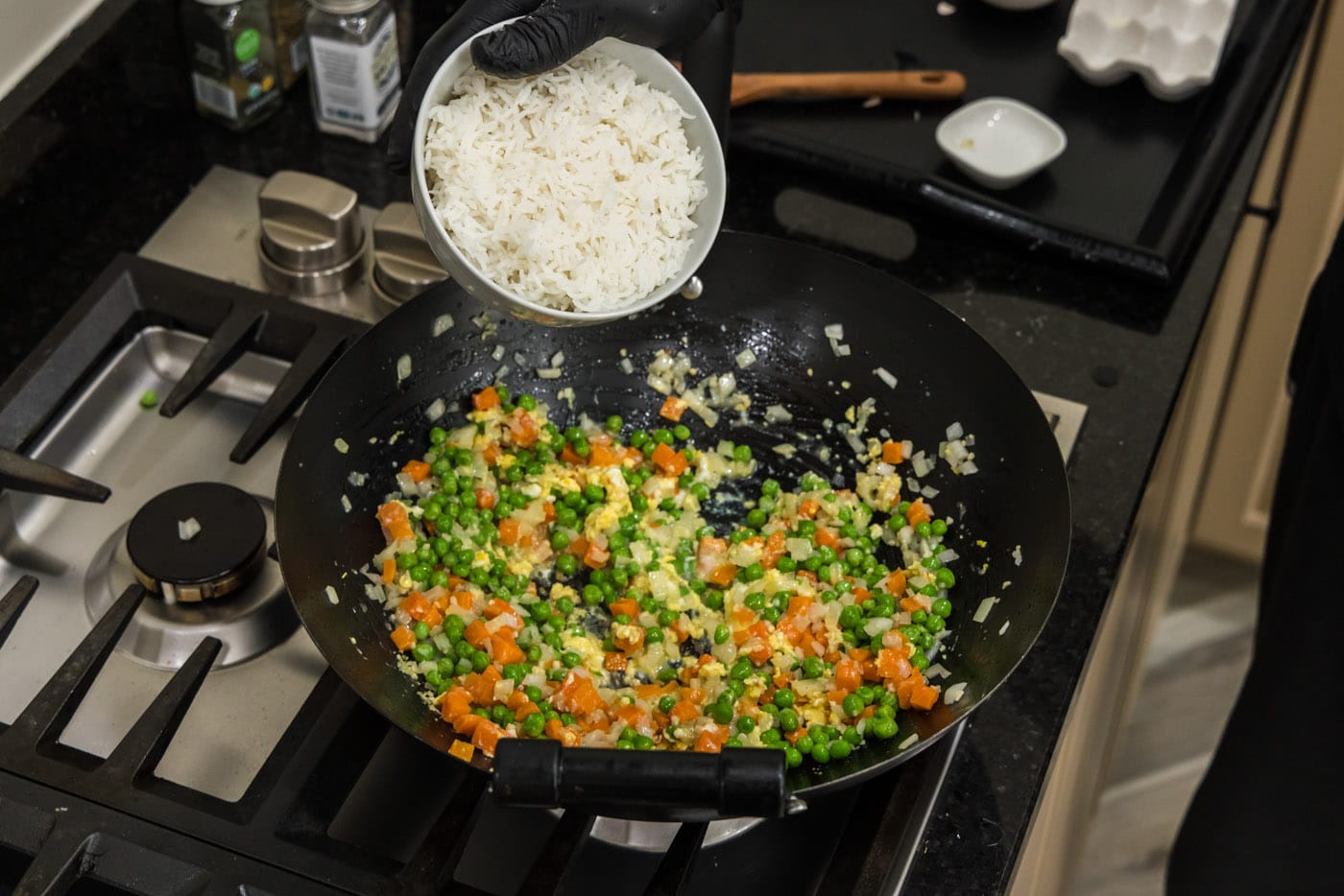 adding cooked rice to wok with vegetables