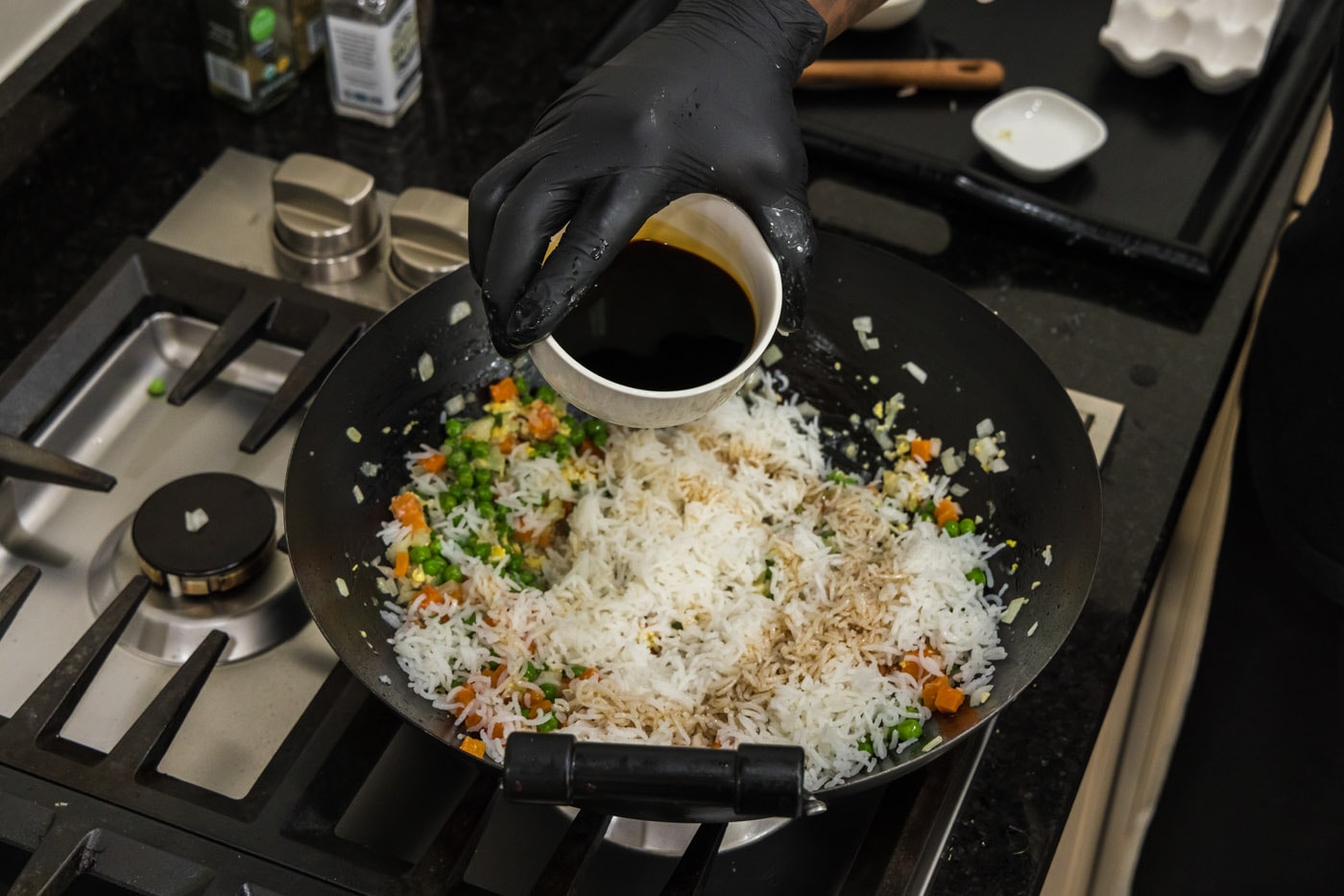 pouring soy sauce into wok with rice and vegetables