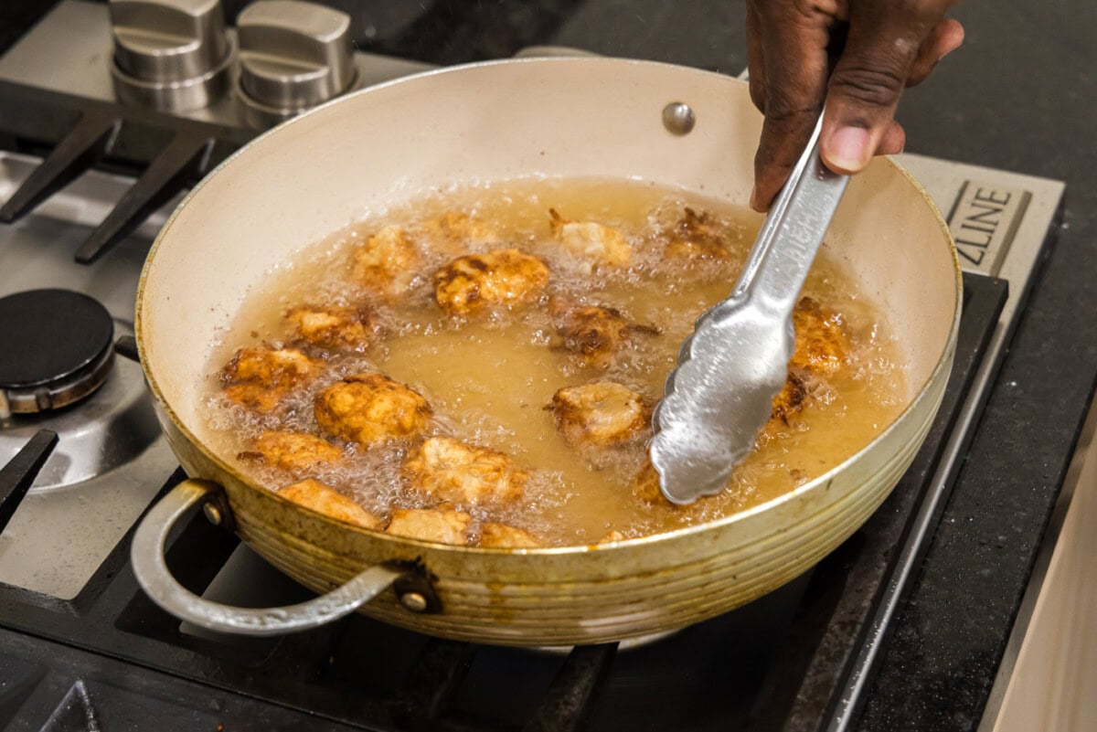 tongs flipping fried pork in oil