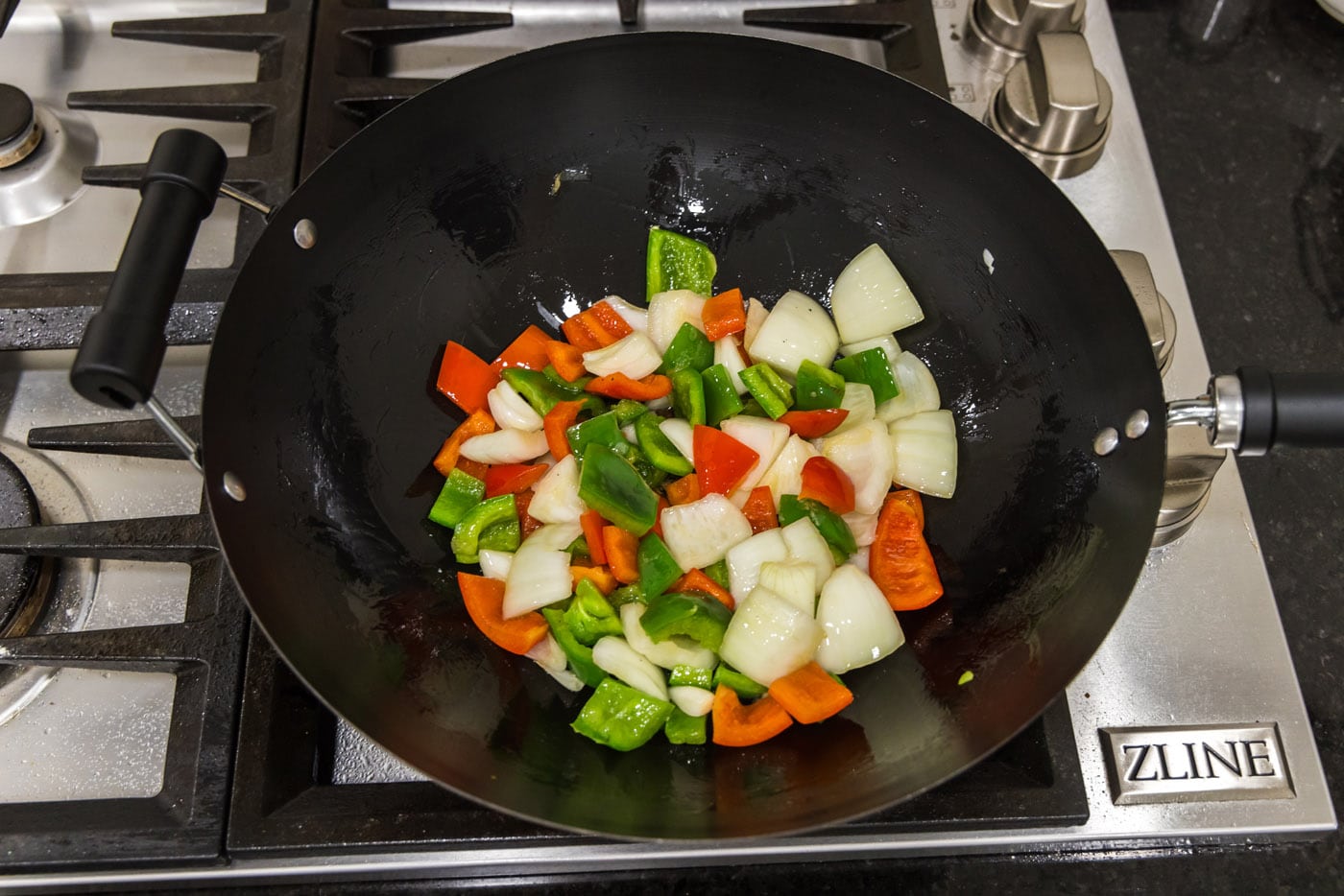 onion and bell peppers in a wok