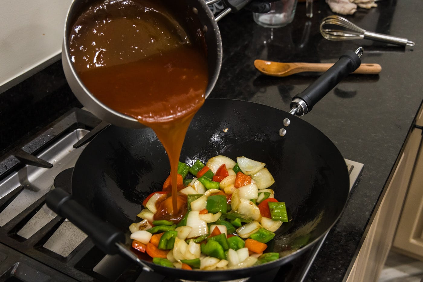 pouring sweet and sour sauce over stir fried vegetables