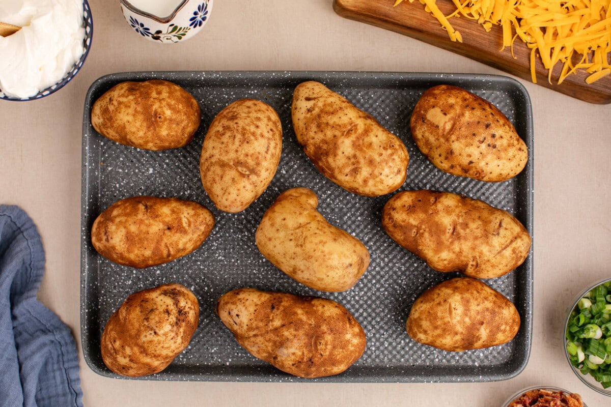 russet potatoes with fork piercings on a baking sheet