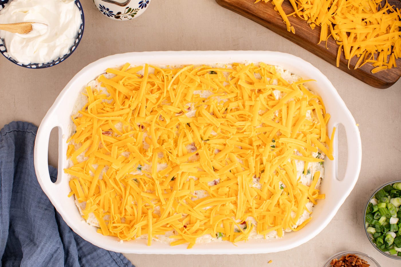 shredded cheddar cheese on top of mashed potato casserole