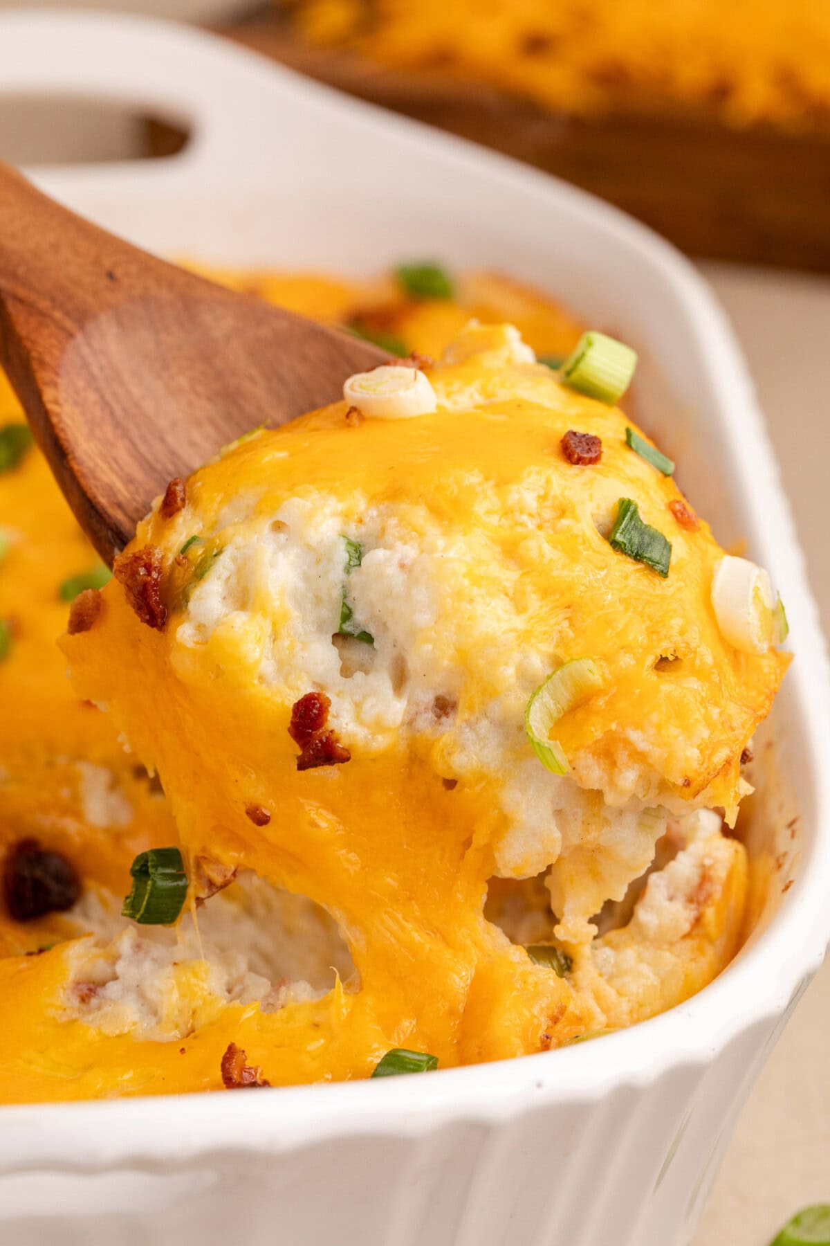 Spoonful of Twice Baked Potato Casserole being lifted out of the casserole dish