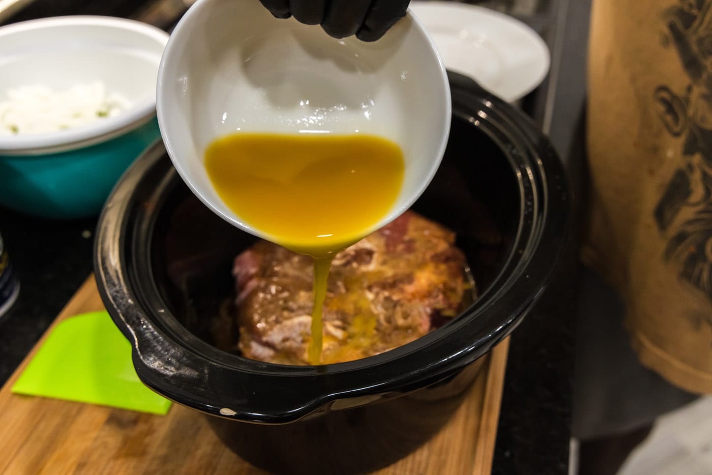 pouring pineapple juice with seasoning over chuck roast in crockpot